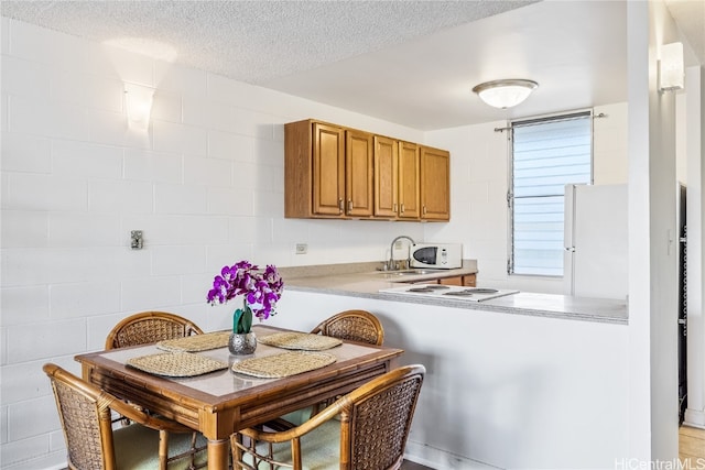 kitchen with kitchen peninsula, a textured ceiling, white appliances, and sink