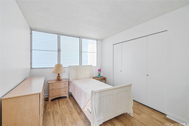 bedroom featuring a textured ceiling, light hardwood / wood-style flooring, and a closet