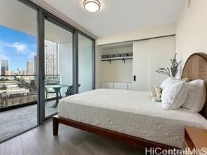 bedroom featuring access to outside, hardwood / wood-style floors, and a wall of windows