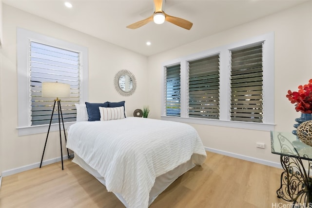 bedroom featuring ceiling fan, multiple windows, and light hardwood / wood-style flooring