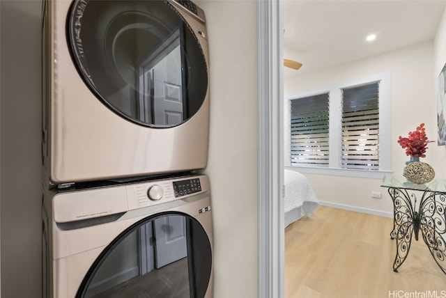 laundry room with light hardwood / wood-style floors and stacked washer / drying machine