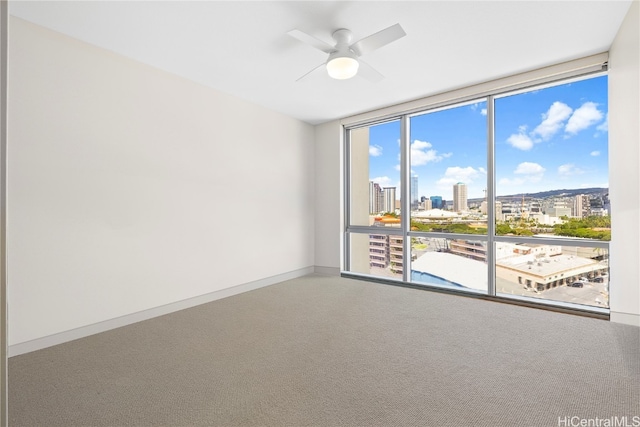 carpeted spare room featuring floor to ceiling windows and ceiling fan