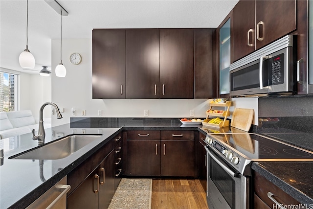 kitchen with dark brown cabinetry, sink, pendant lighting, appliances with stainless steel finishes, and light wood-type flooring