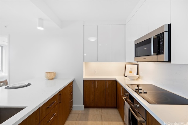 kitchen featuring white cabinets, stainless steel appliances, and light tile patterned floors