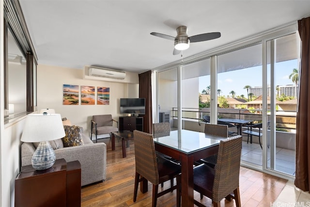 dining room with wood-type flooring, a wall unit AC, and ceiling fan