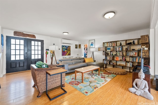 living room with light hardwood / wood-style floors, french doors, and a wall mounted AC