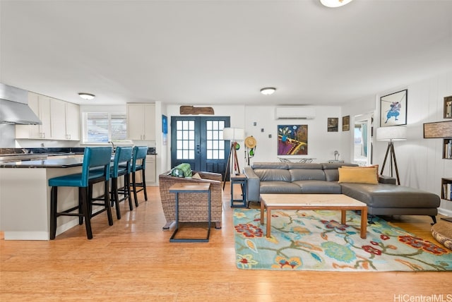 living room featuring french doors, a wall mounted AC, and light hardwood / wood-style floors