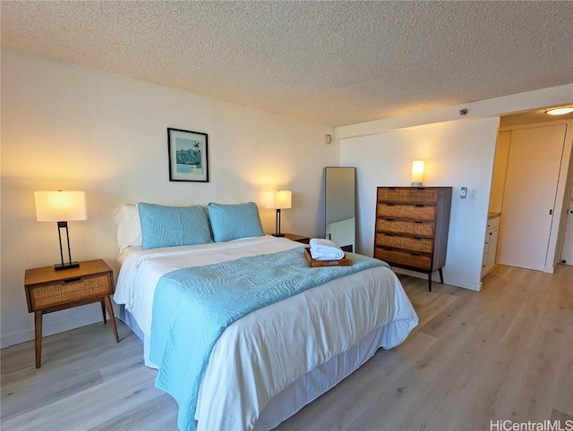 bedroom featuring a textured ceiling and light hardwood / wood-style flooring