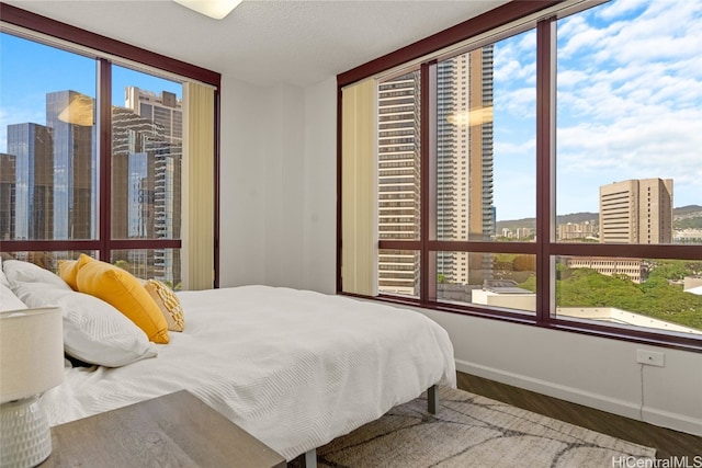 bedroom with wood-type flooring, a textured ceiling, and multiple windows