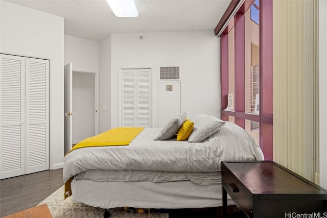 bedroom with multiple closets, dark hardwood / wood-style flooring, and a textured ceiling