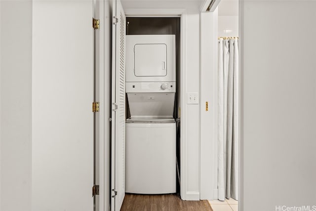 laundry room with wood-type flooring and stacked washer / dryer