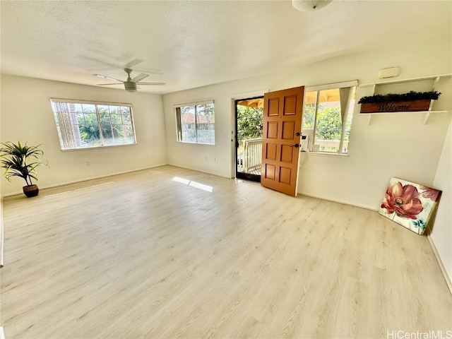 unfurnished living room with a textured ceiling, light hardwood / wood-style floors, and ceiling fan