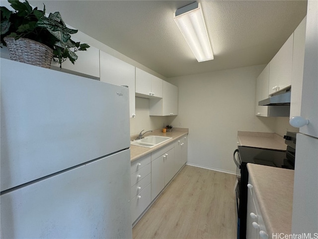 kitchen with stainless steel refrigerator, stove, white cabinets, and light wood-type flooring