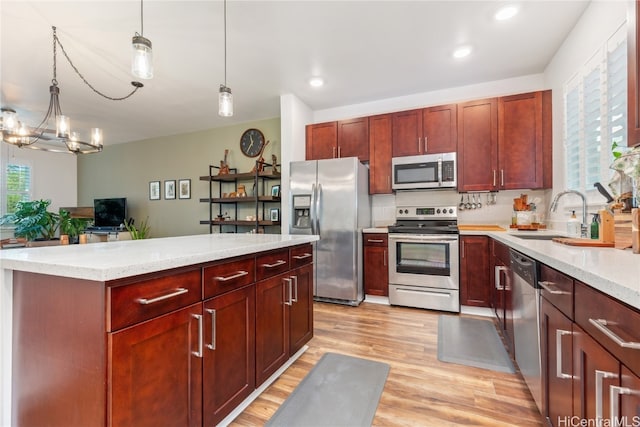 kitchen with sink, decorative light fixtures, light hardwood / wood-style flooring, appliances with stainless steel finishes, and a notable chandelier