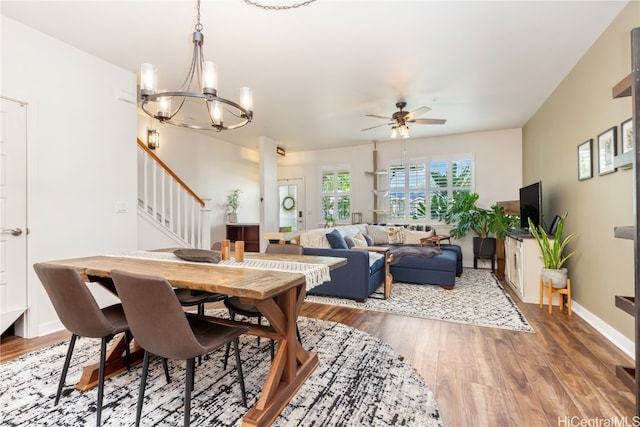 dining area with wood-type flooring and ceiling fan with notable chandelier