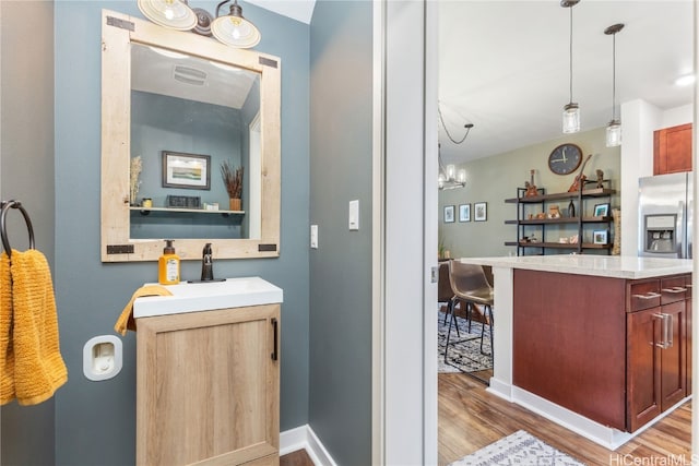 bathroom with a chandelier, vanity, and wood-type flooring