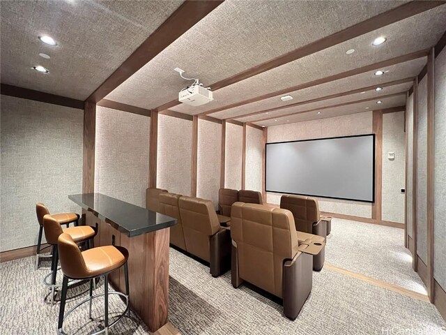 cinema room featuring beam ceiling, light colored carpet, and a textured ceiling