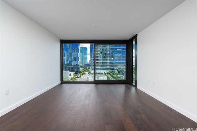 empty room with a wall of windows and dark wood-type flooring