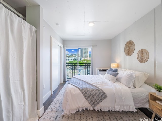 bedroom featuring a wall mounted air conditioner, hardwood / wood-style floors, and access to outside