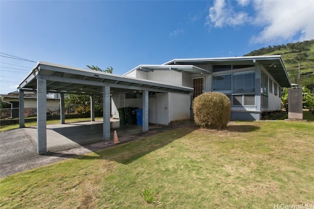 rear view of house featuring a lawn and a carport