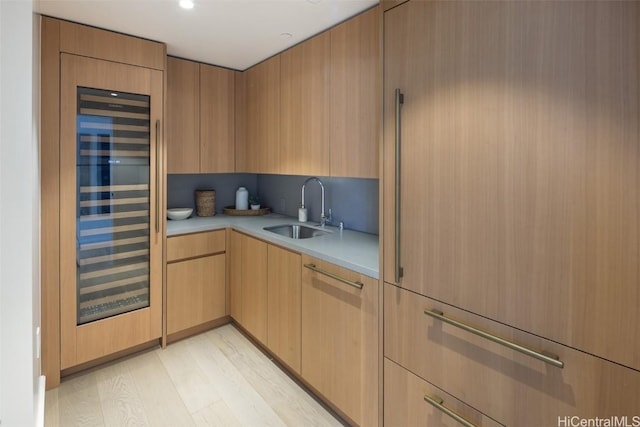 kitchen featuring light brown cabinetry, light wood-type flooring, sink, and beverage cooler