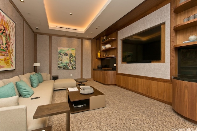 cinema with a tray ceiling, wood walls, and light carpet