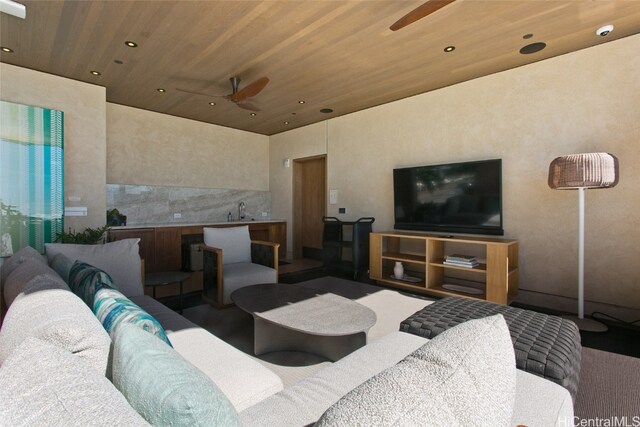 living room featuring ceiling fan, wooden ceiling, and sink