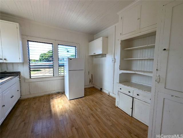 kitchen with white cabinets, light hardwood / wood-style flooring, white fridge, and ornamental molding