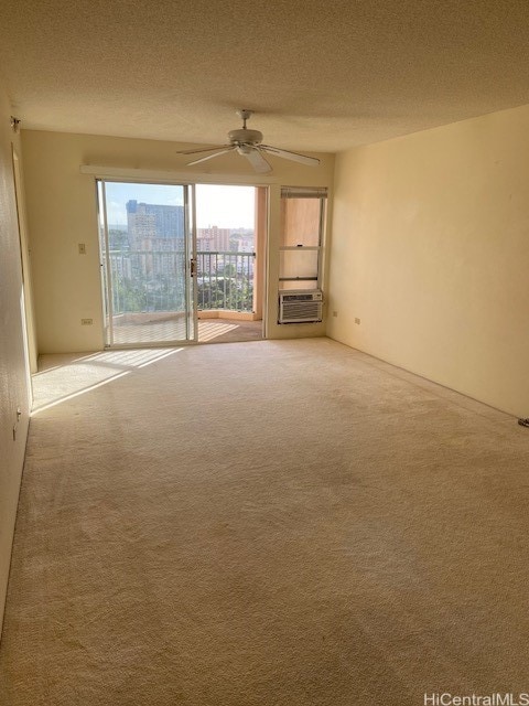 empty room featuring cooling unit, ceiling fan, carpet, and a textured ceiling