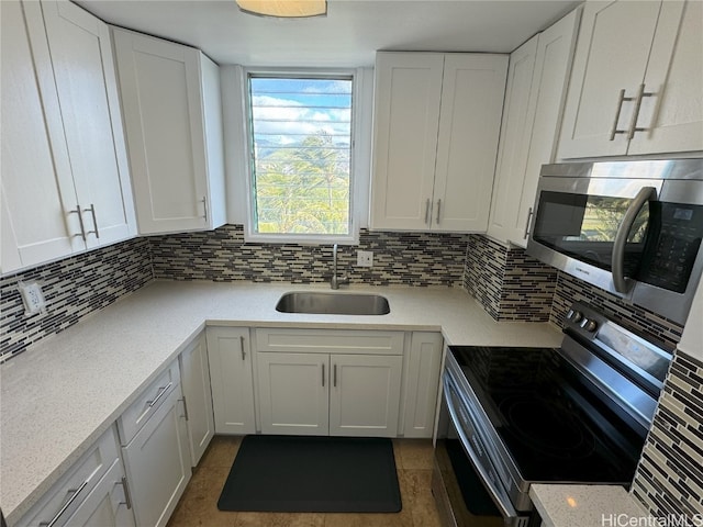 kitchen with appliances with stainless steel finishes, backsplash, dark tile patterned floors, sink, and white cabinetry