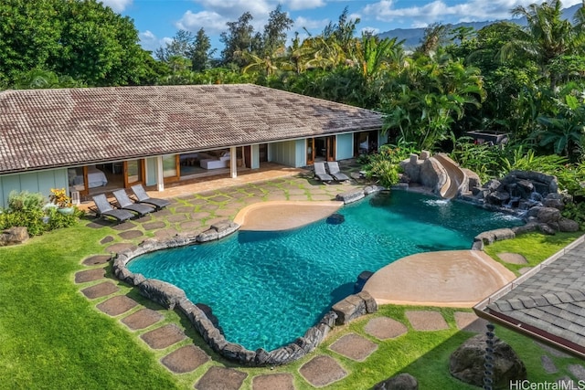 view of swimming pool with a yard, a patio, and a water slide