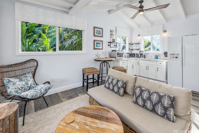 living room featuring hardwood / wood-style floors, vaulted ceiling with beams, and ceiling fan