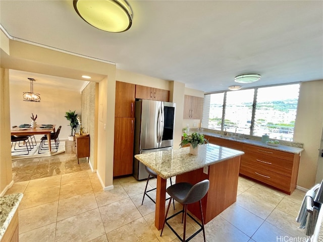 kitchen featuring pendant lighting, stove, a kitchen island, a kitchen bar, and stainless steel refrigerator