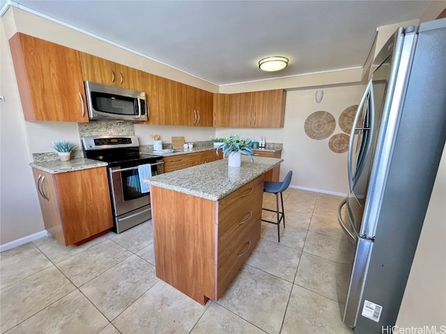 kitchen featuring a breakfast bar, a kitchen island, light tile patterned floors, and appliances with stainless steel finishes