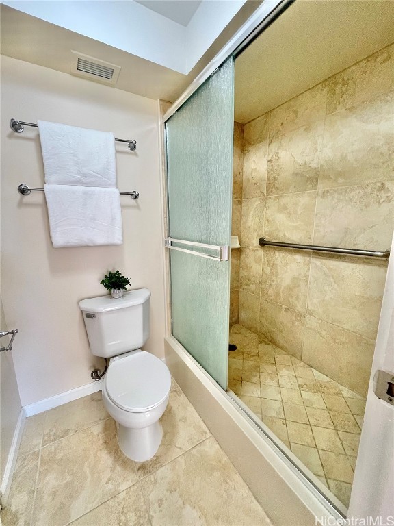 bathroom featuring tile patterned flooring, a shower with shower door, and toilet