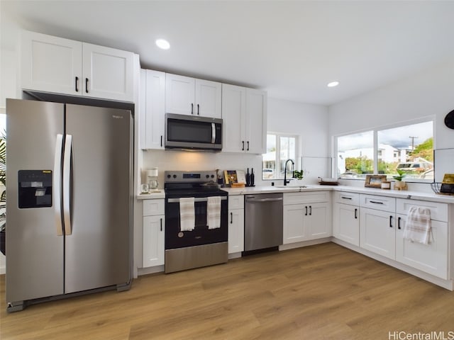 kitchen with backsplash, sink, light wood-type flooring, appliances with stainless steel finishes, and white cabinetry