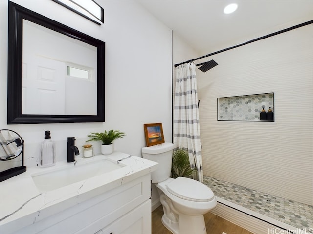 bathroom featuring toilet, hardwood / wood-style floors, vanity, and walk in shower