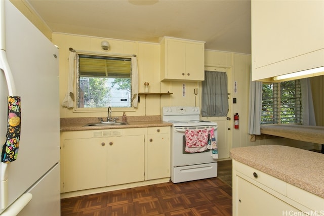 kitchen with a healthy amount of sunlight, dark parquet flooring, white appliances, and sink