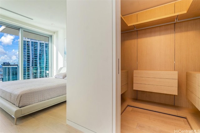 bedroom with multiple windows, light hardwood / wood-style flooring, and floor to ceiling windows