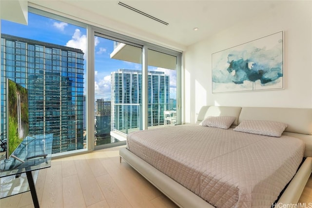 bedroom with light hardwood / wood-style flooring and a wall of windows