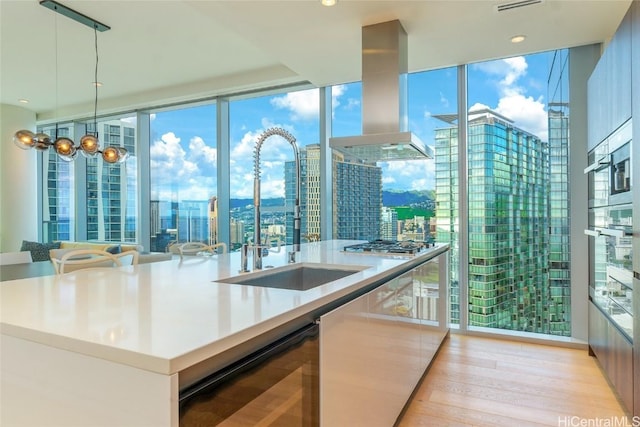 kitchen featuring pendant lighting, floor to ceiling windows, sink, wine cooler, and wall chimney exhaust hood