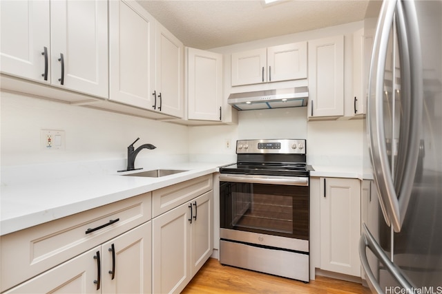 kitchen with light hardwood / wood-style floors, white cabinetry, sink, and appliances with stainless steel finishes