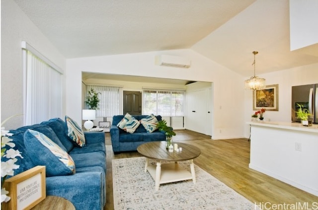 living room featuring an AC wall unit, a chandelier, vaulted ceiling, and hardwood / wood-style flooring