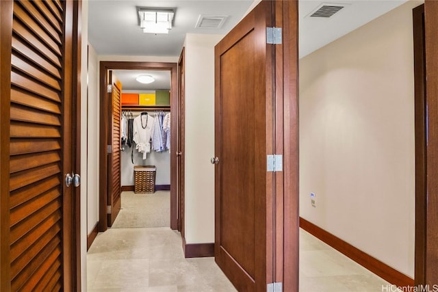 hallway featuring baseboards and visible vents