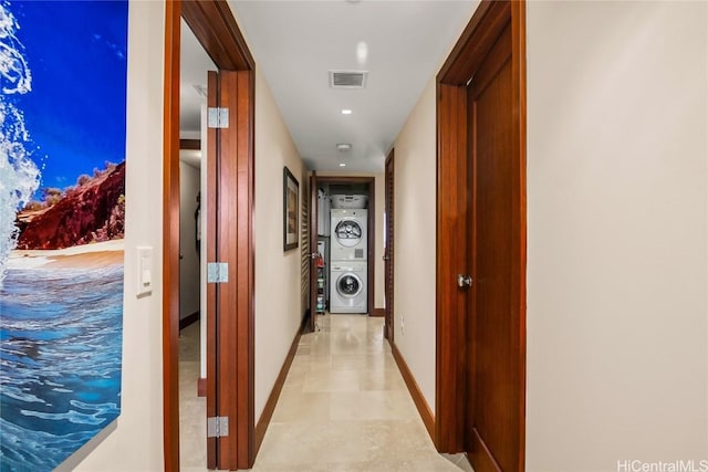 corridor with visible vents, stacked washer / drying machine, and baseboards