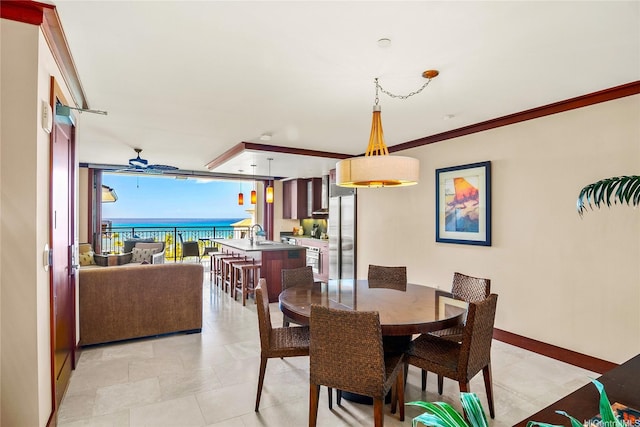 dining room featuring light tile patterned flooring, a water view, baseboards, and ornamental molding
