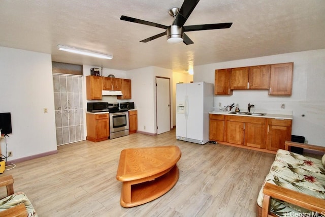 kitchen with ceiling fan, sink, stainless steel appliances, a textured ceiling, and light wood-type flooring