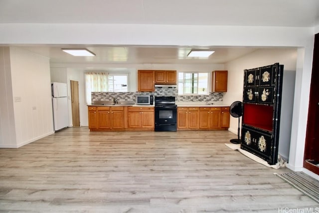 kitchen with backsplash, black electric range, light wood-type flooring, and white refrigerator