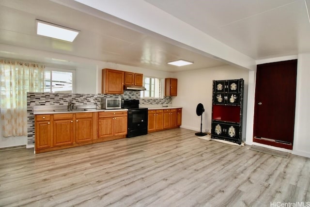 kitchen featuring black electric range oven, sink, light hardwood / wood-style flooring, and tasteful backsplash