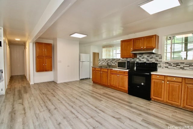 kitchen with sink, black range with electric cooktop, light hardwood / wood-style flooring, backsplash, and white fridge